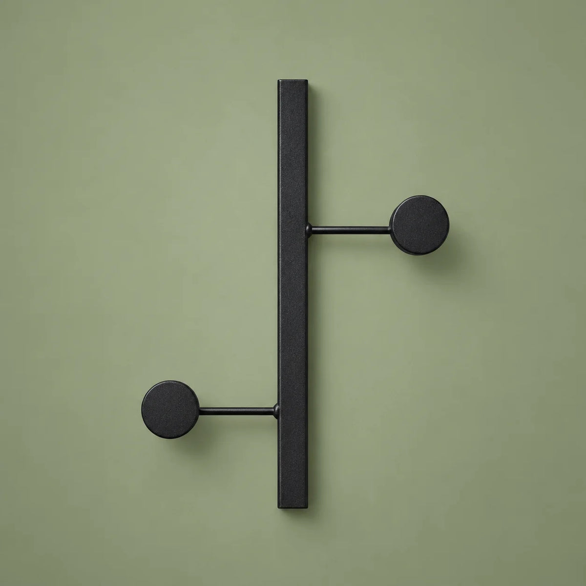 Vue complète du porte-manteau mural noir à deux crochets sur fond vert sauge