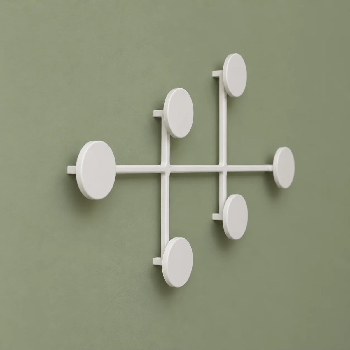 Vue en perspective des six patères rondes du porte-manteau mural blanc sur fond vert sauge