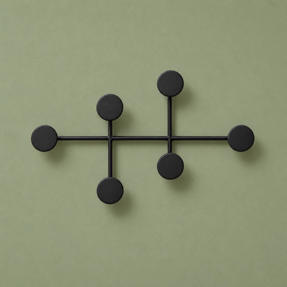Porte-manteau mural noir à six patères circulaires, vue entière sur fond vert sauge