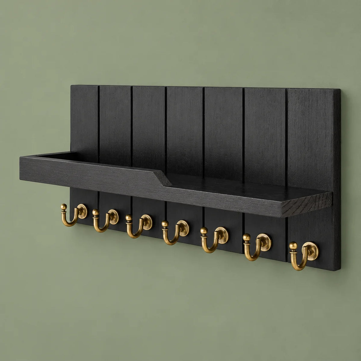 Vue complète du porte-manteau mural noir à tablette et sept crochets dorés sur fond vert sauge