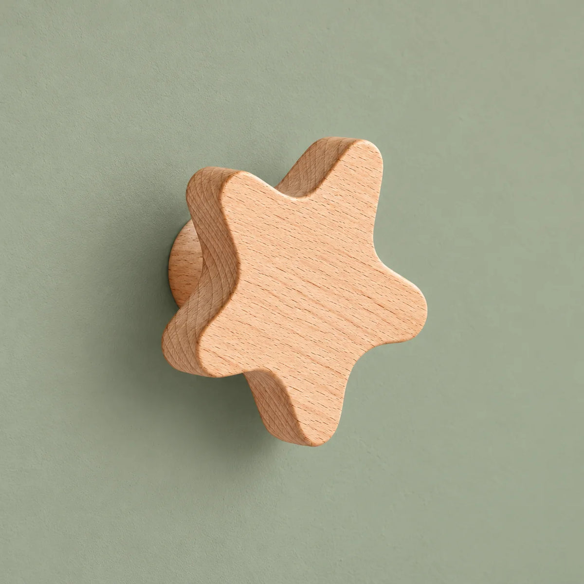 Patère murale étoile en bois naturel présentée seule sur fond vert sauge