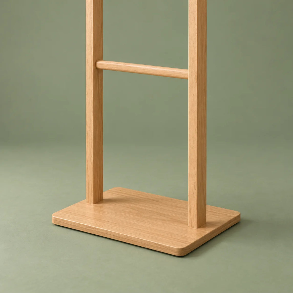 Détail du socle plat et des deux montants du porte-manteau en bois clair