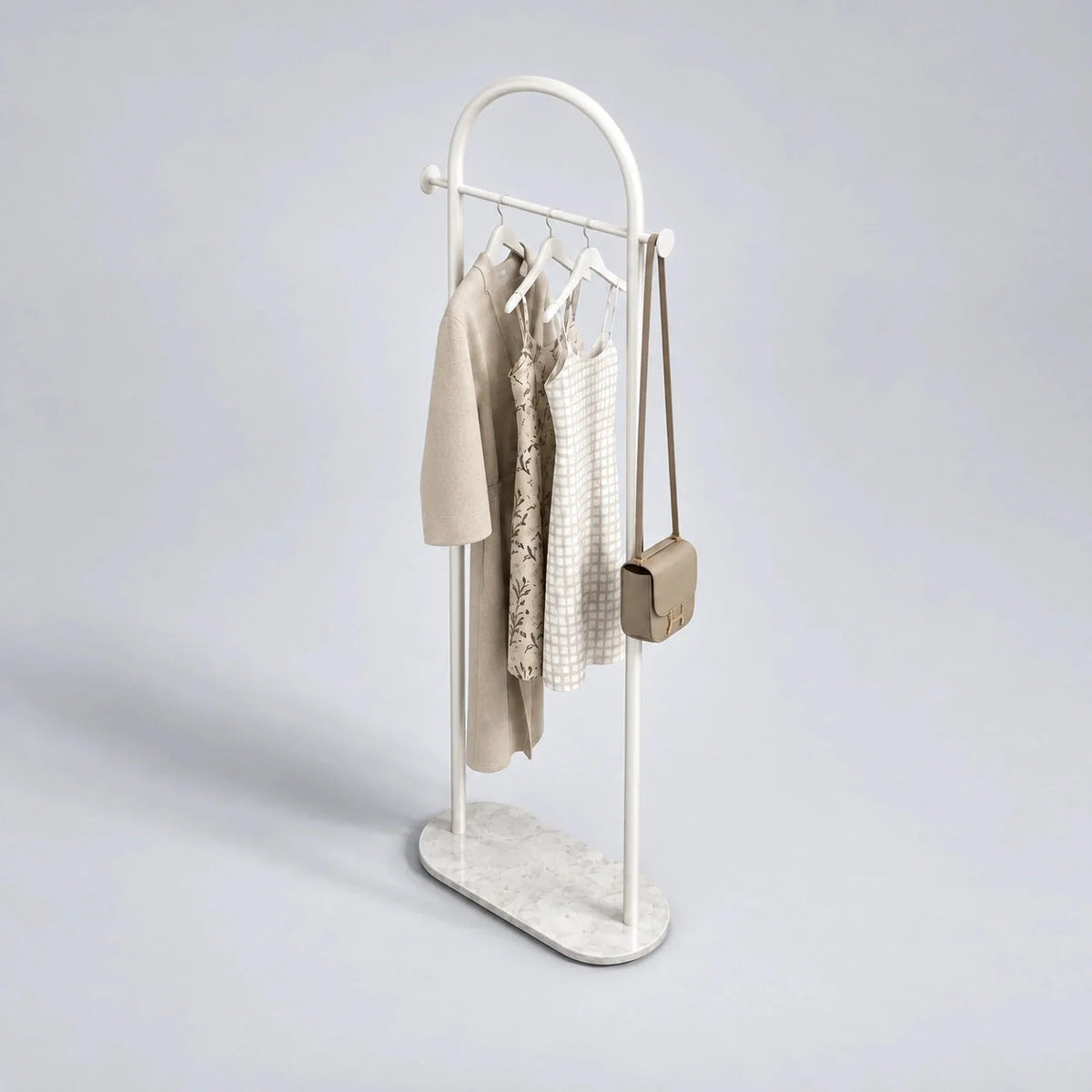 Porte-manteau courbé blanc vu de trois quarts avec vêtements suspendus