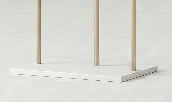 Détail de la base rectangulaire blanche et des trois montants dorés du porte-manteau