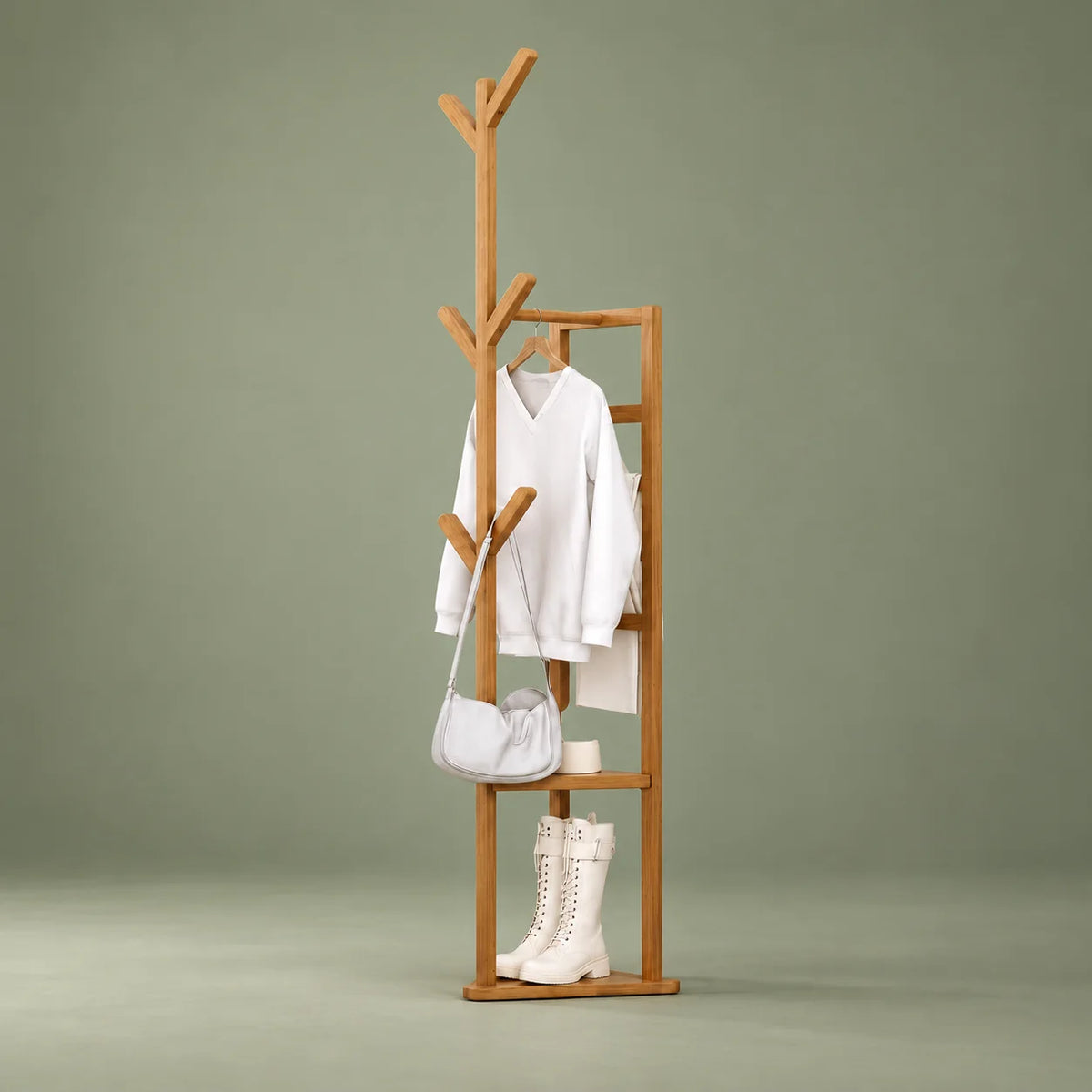 Porte-manteau multifonction en bois clair avec vêtement et bottes sur fond vert sauge