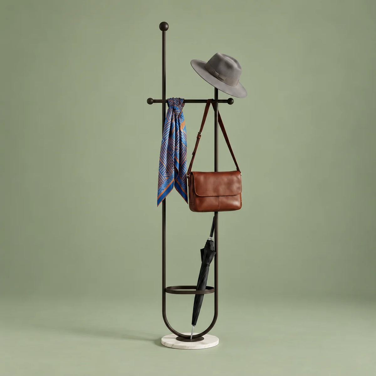 Porte-manteau sur pied en métal noir avec chapeau, foulard, sac et parapluie, anneau porte-parapluie et base ronde blanche veinée sur fond vert sauge
