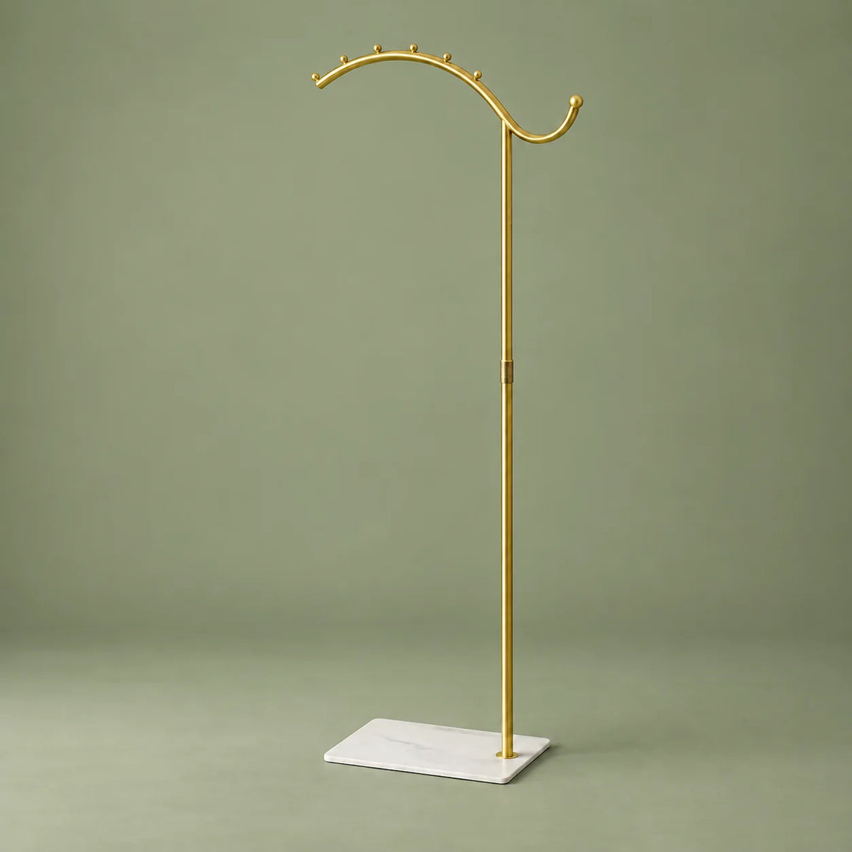 Porte-manteau voûté doré à socle blanc, vue complète sur fond vert sauge
