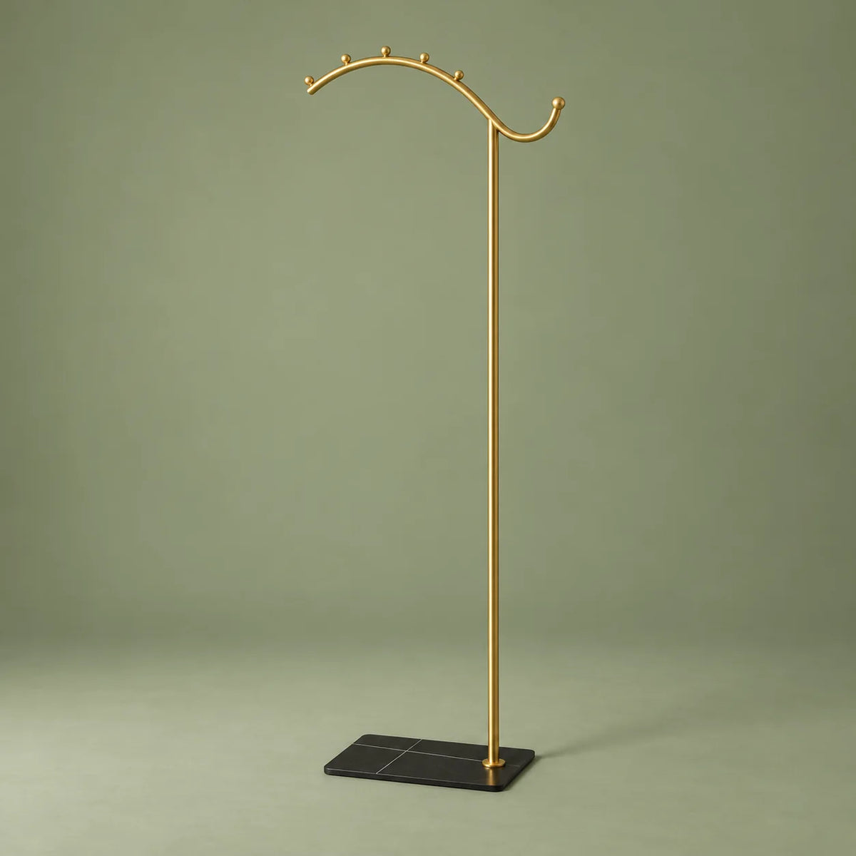 Porte-manteau voûte dorée à socle noir, vue complète sur fond vert sauge