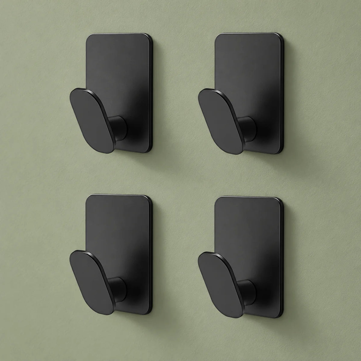Les quatre crochets noirs du lot disposés sur un fond vert sauge