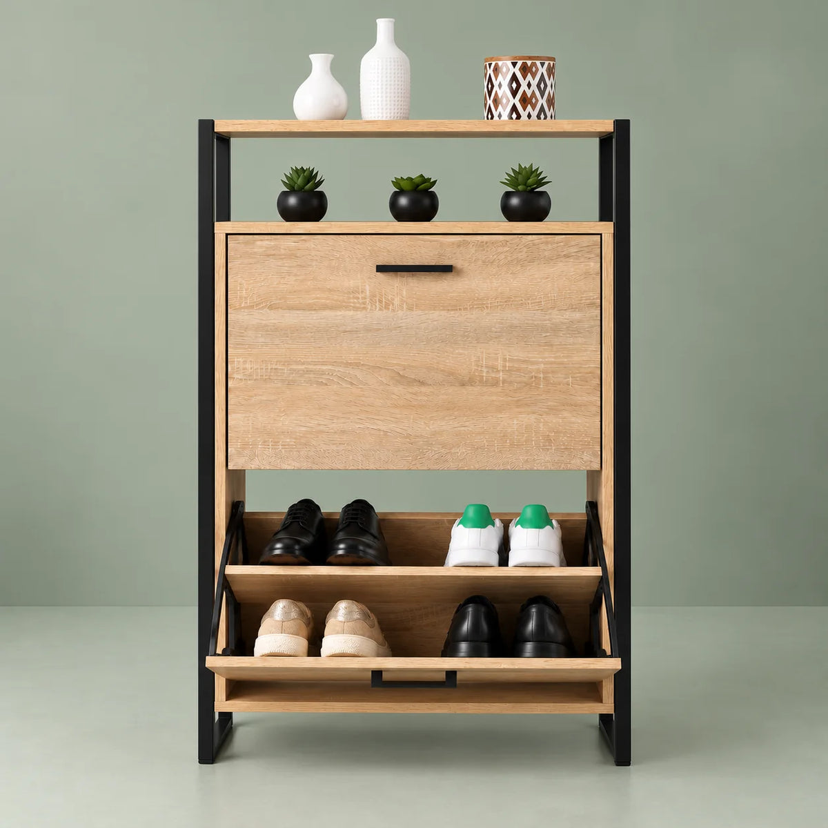 Vue de face du meuble à chaussures industriel avec rangement bas ouvert sur fond vert sauge