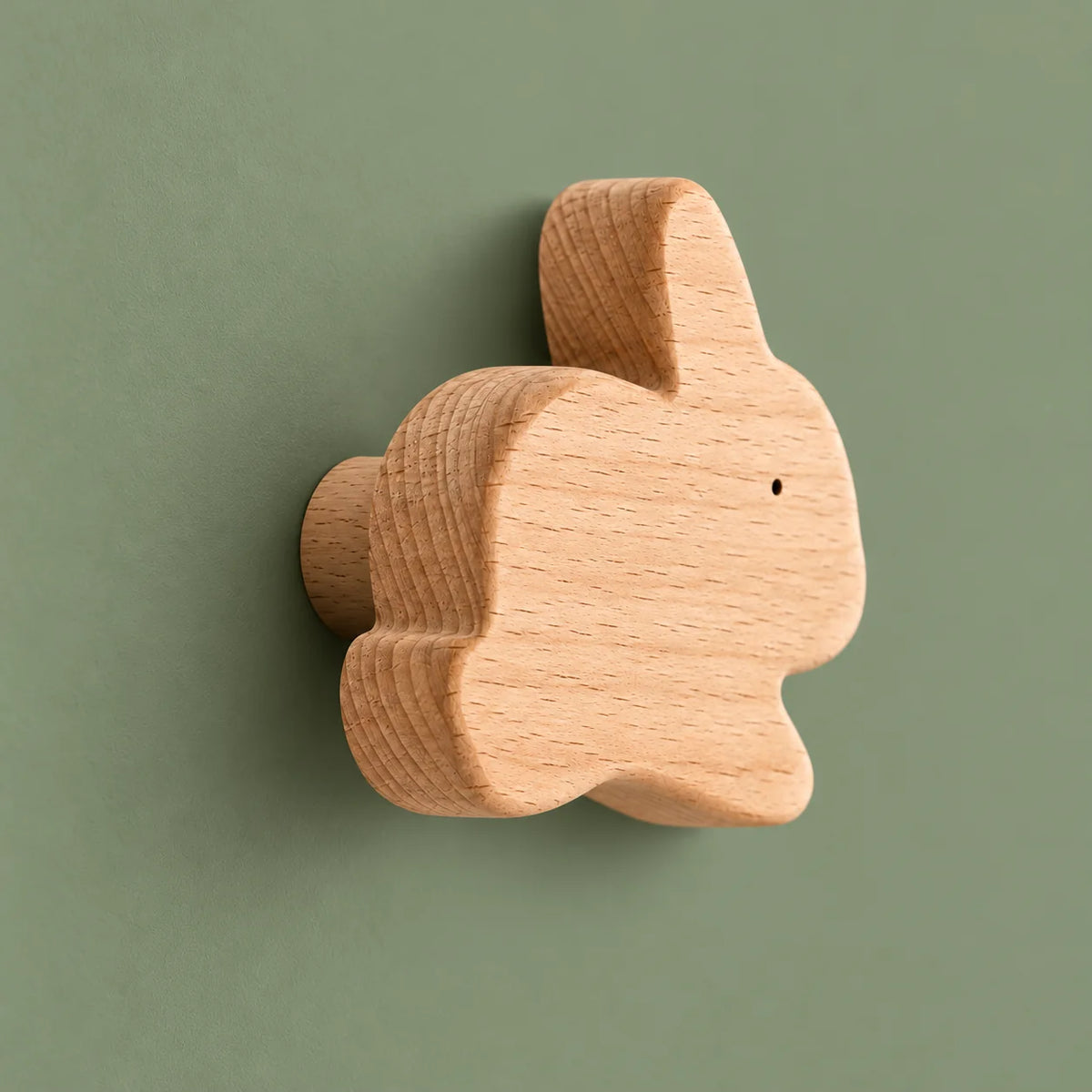 Vue de biais de la patère lapin montrant son épaisseur et son support cylindrique sur fond vert