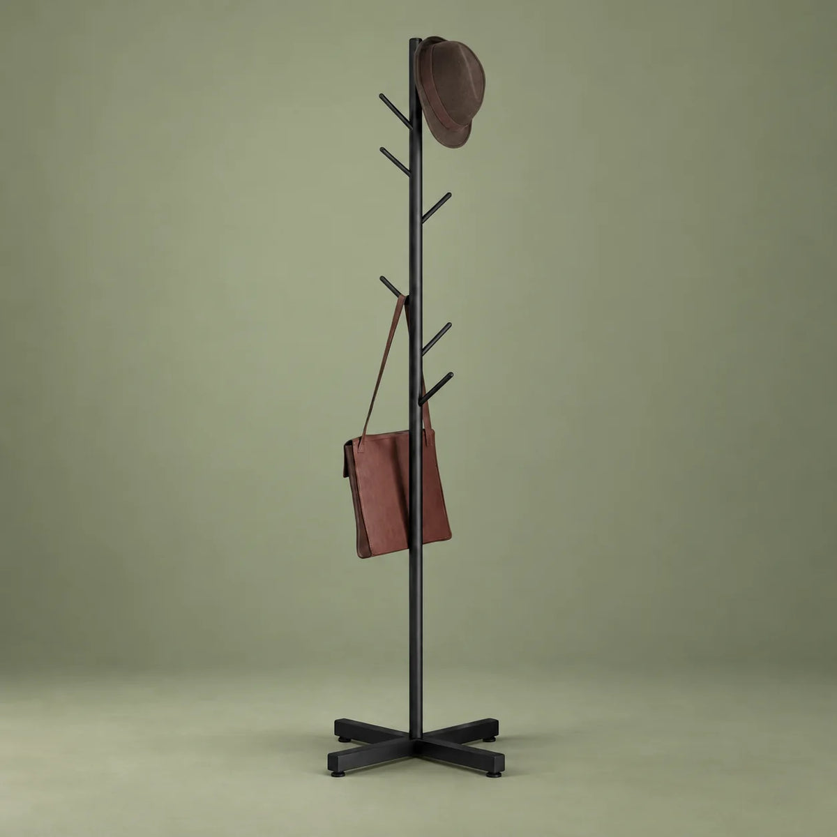 Porte-manteau arbre noir sur sa base croisée devant un fond vert sauge