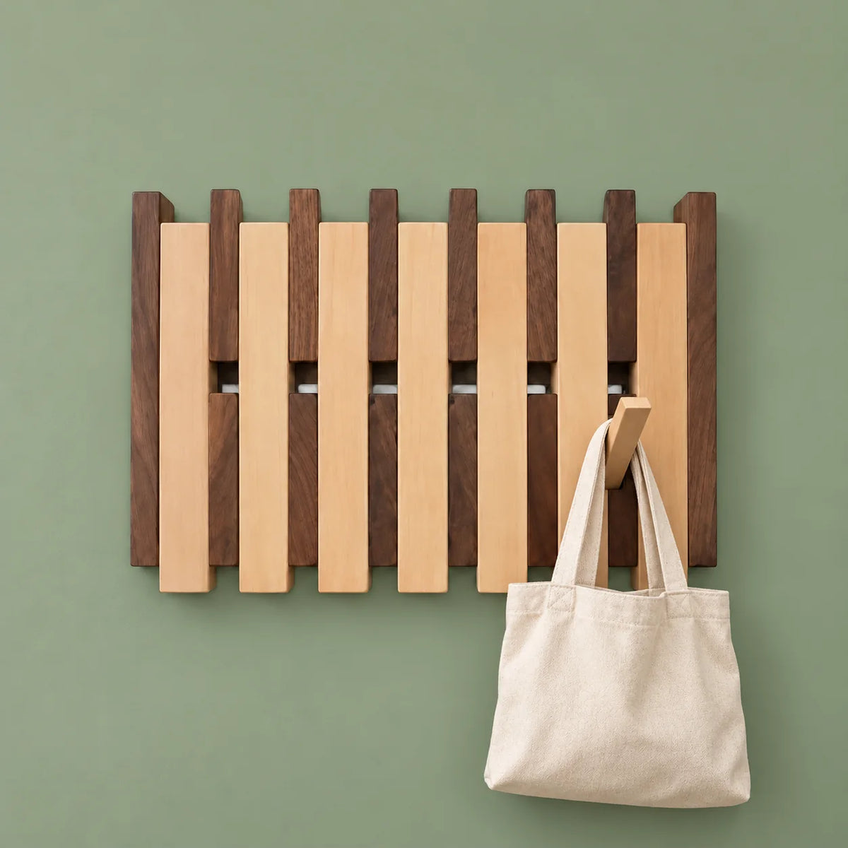 Grand porte-manteau mural bicolore portant un sac en toile sur fond vert sauge