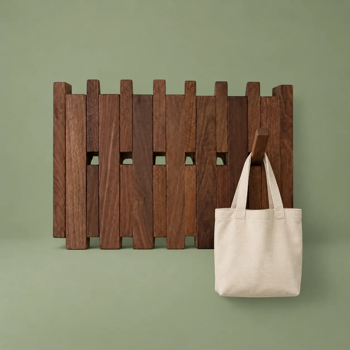 Porte-manteau mural large en bois foncé portant un sac en tissu sur fond vert sauge
