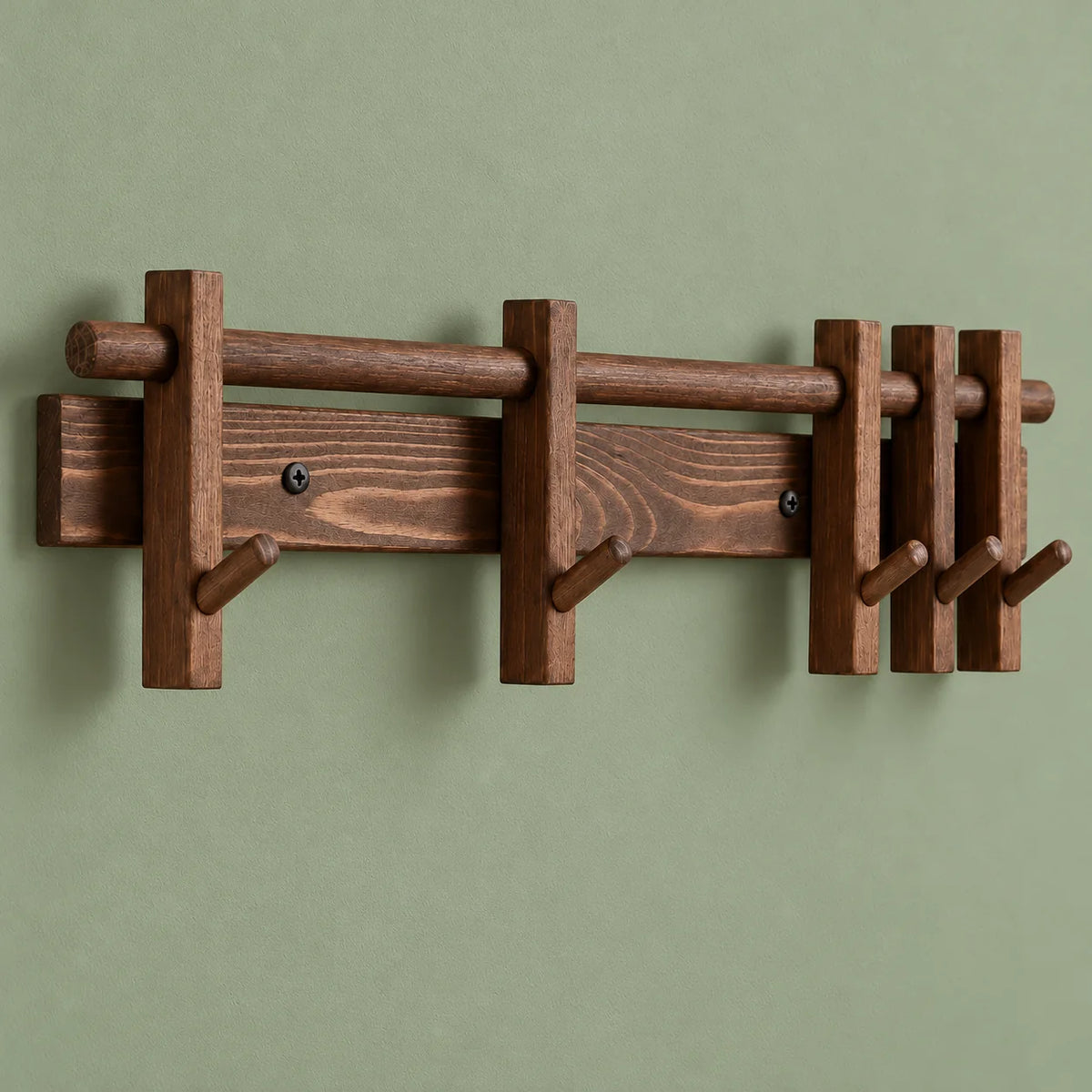 Vue de trois quarts du porte-manteau mural en bois foncé sur mur vert sauge