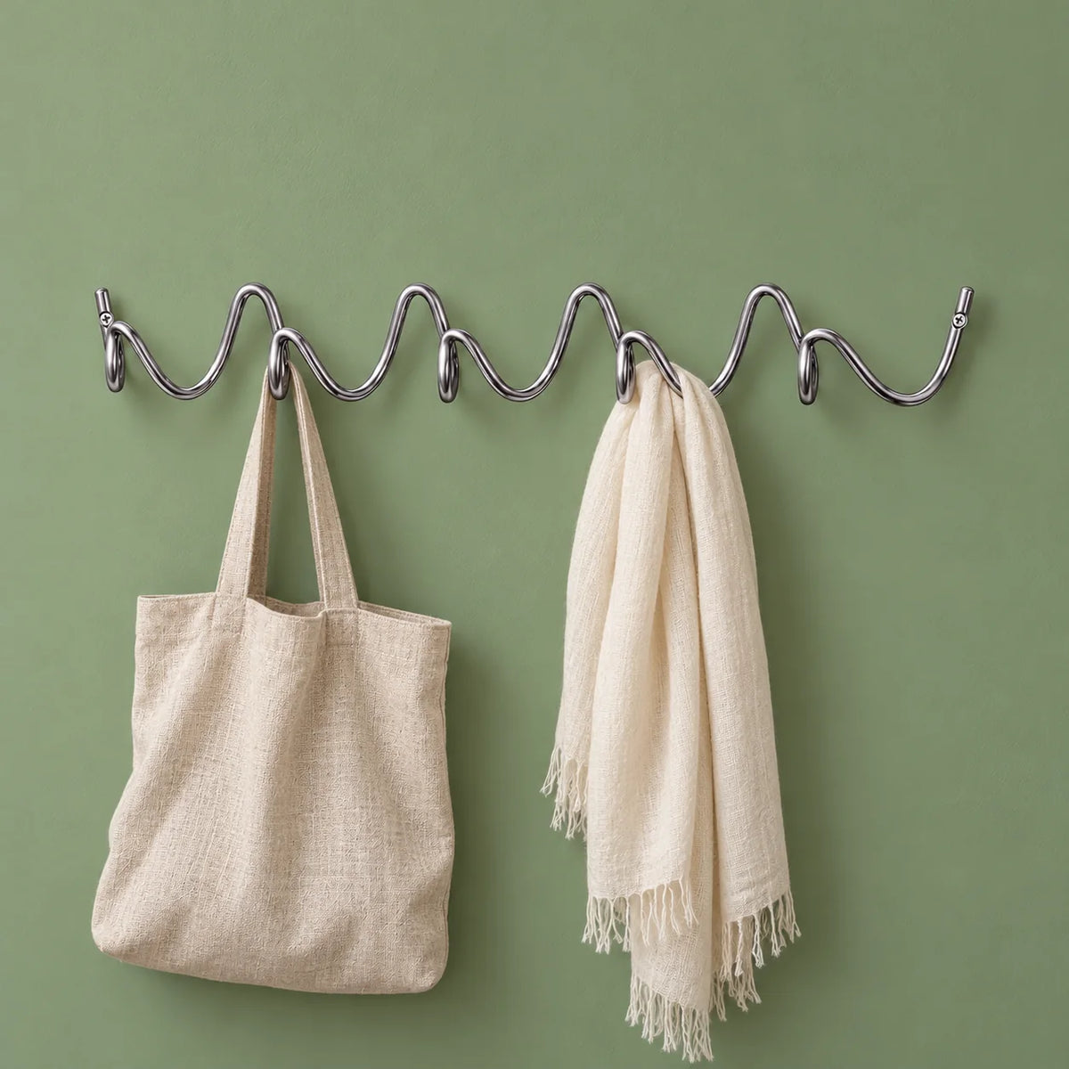 Porte-manteau mural Vrille chrome avec sac en lin et écharpe sur fond vert sauge