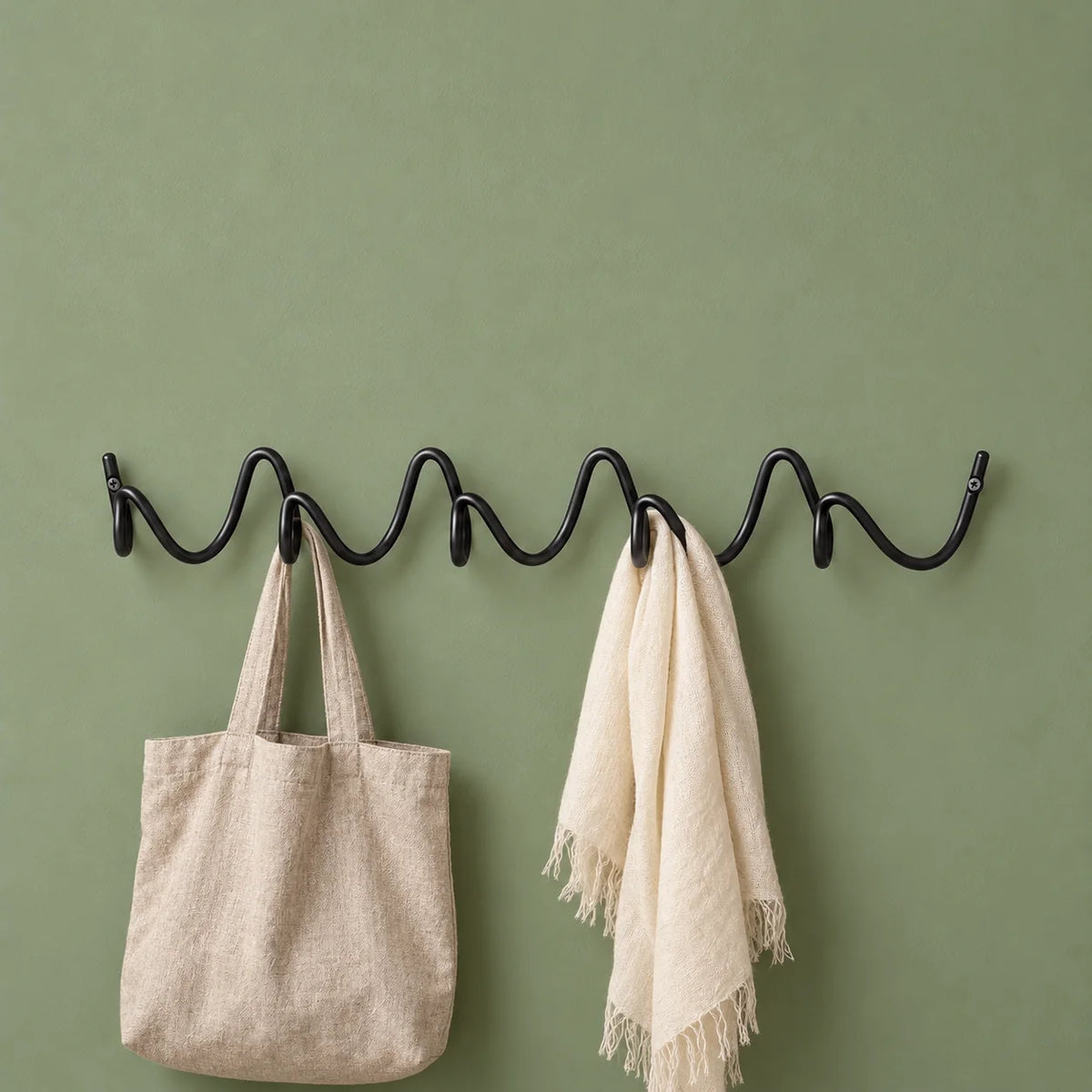 Porte-manteau mural Vrille noir avec sac en lin et écharpe sur fond vert sauge