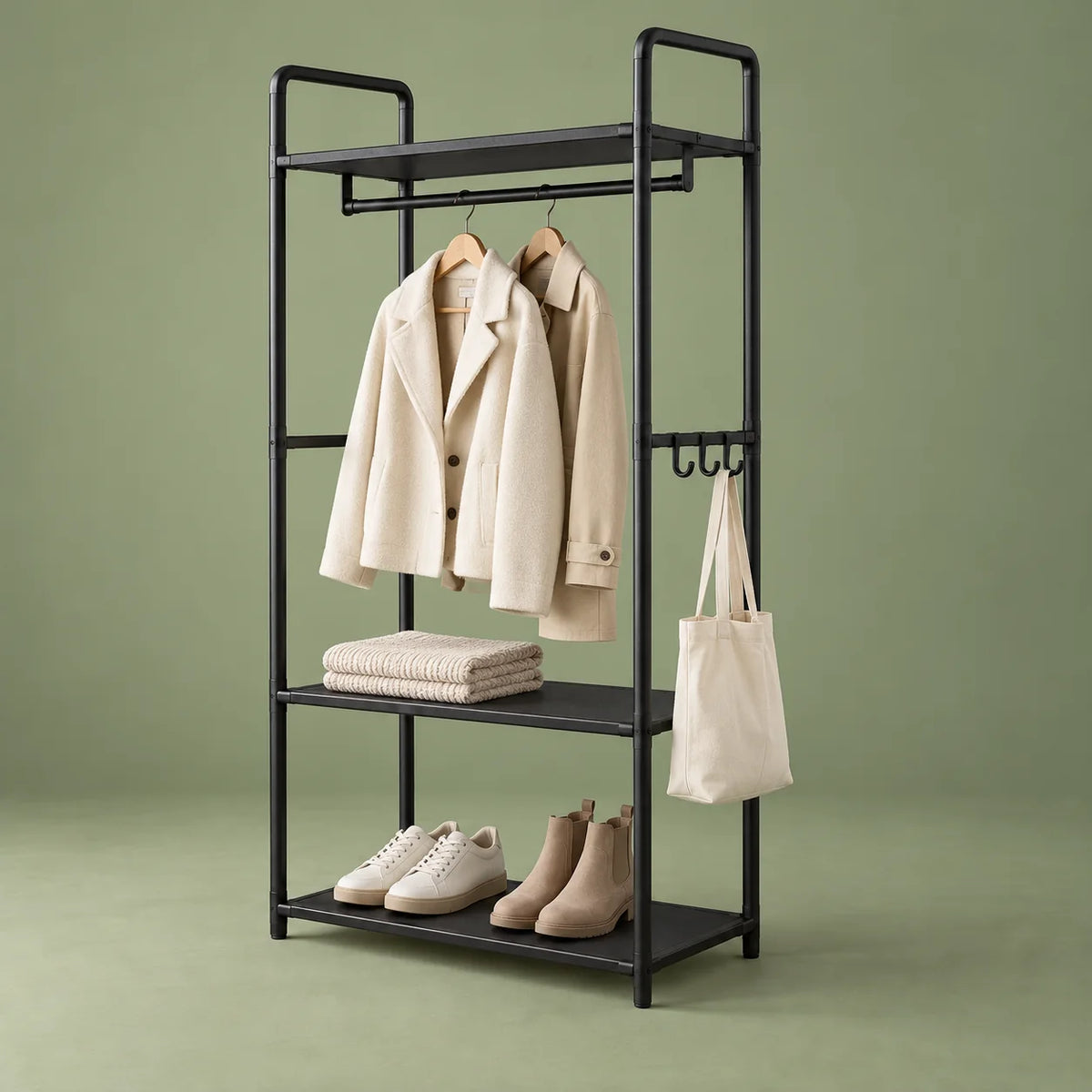 Porte-manteau meuble noir avec deux manteaux et chaussures sur fond vert sauge