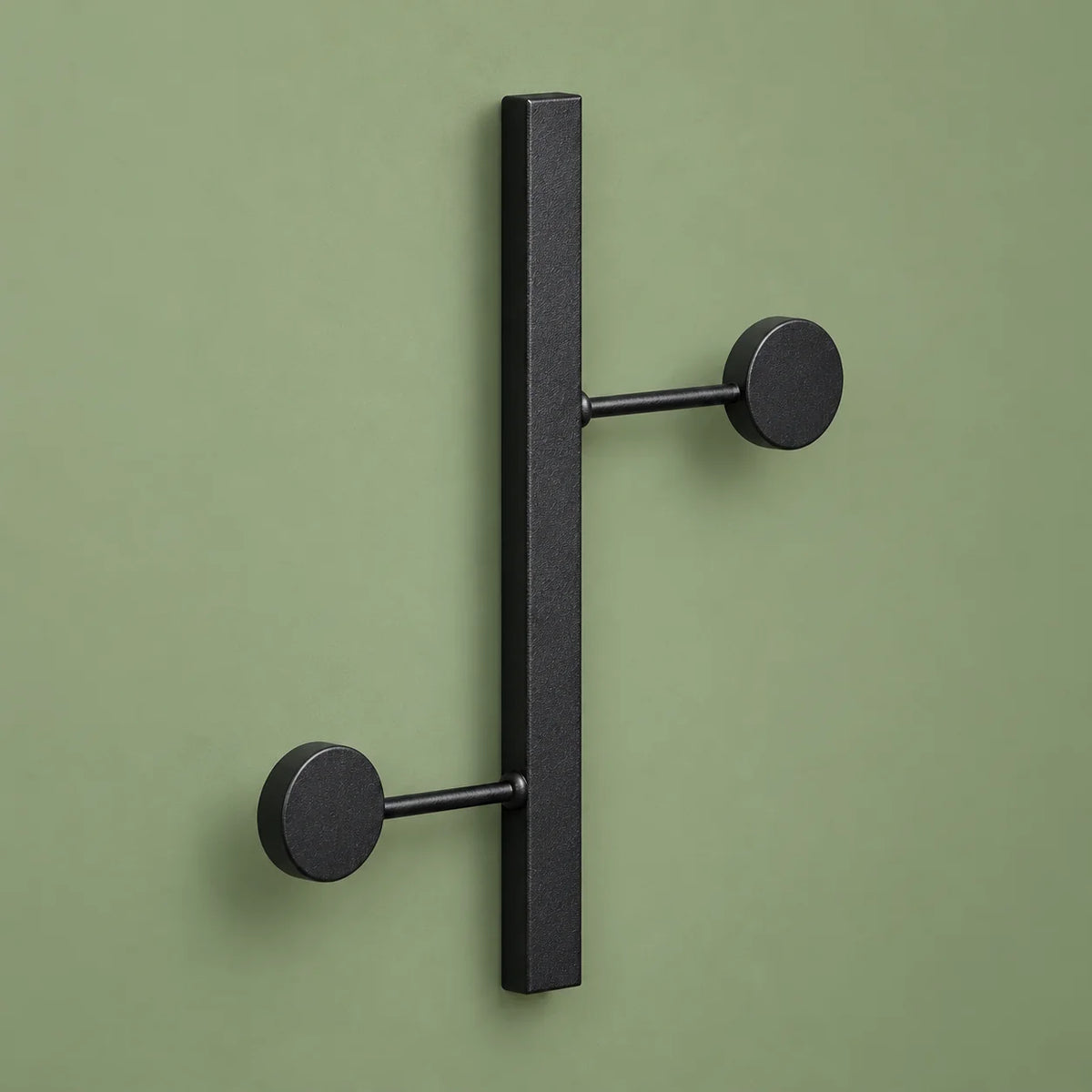 Vue oblique des deux crochets ronds en métal noir sur fond vert sauge