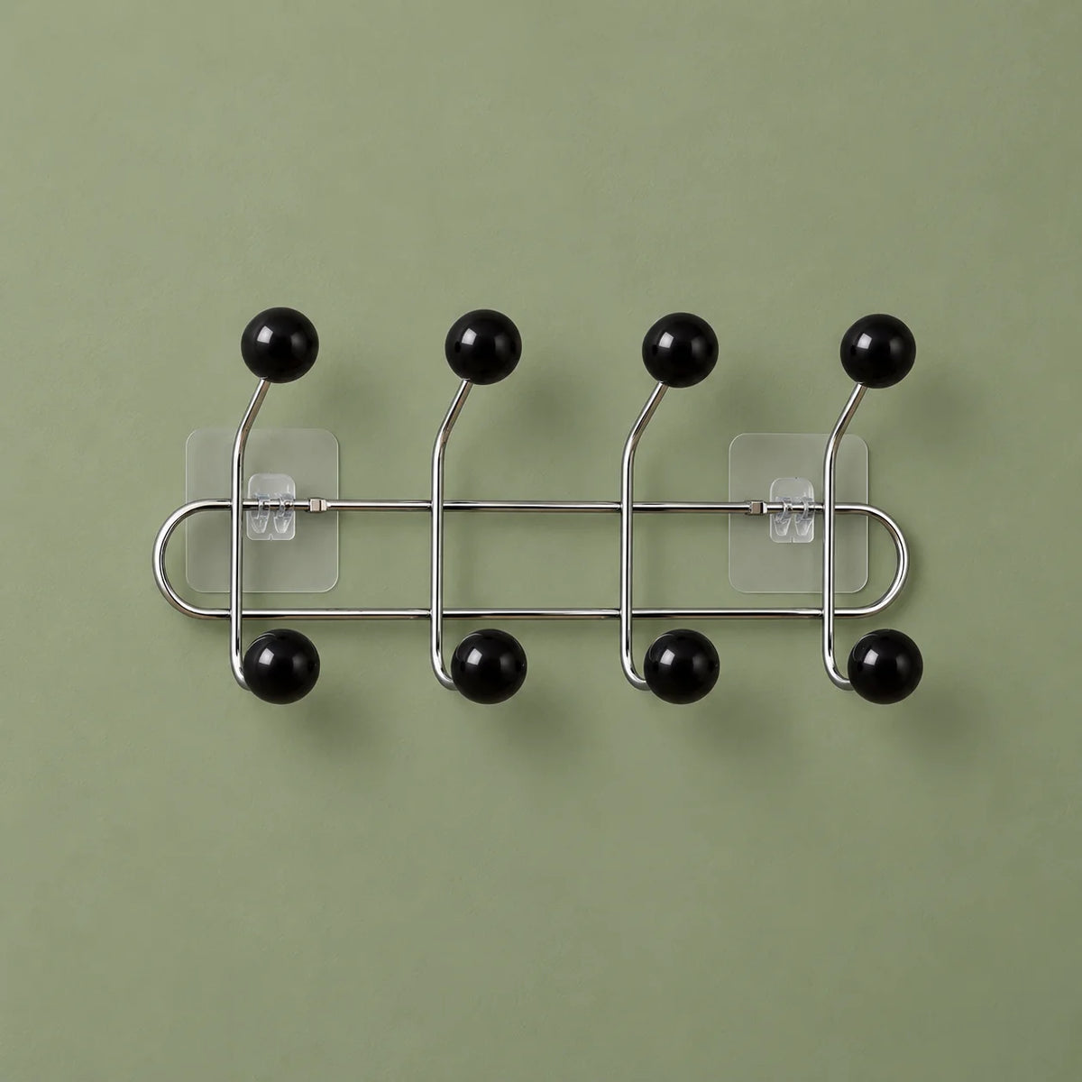 Porte-manteau mural chromé à quatre bras et huit boules noires sur fond vert sauge