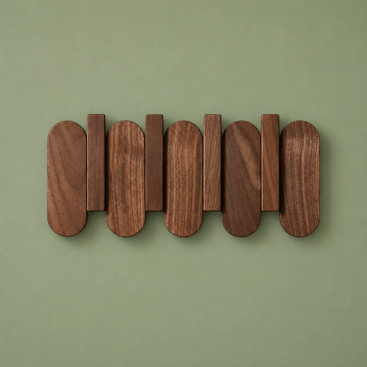 Petit porte-manteau mural en bois foncé vu de face sur fond vert sauge