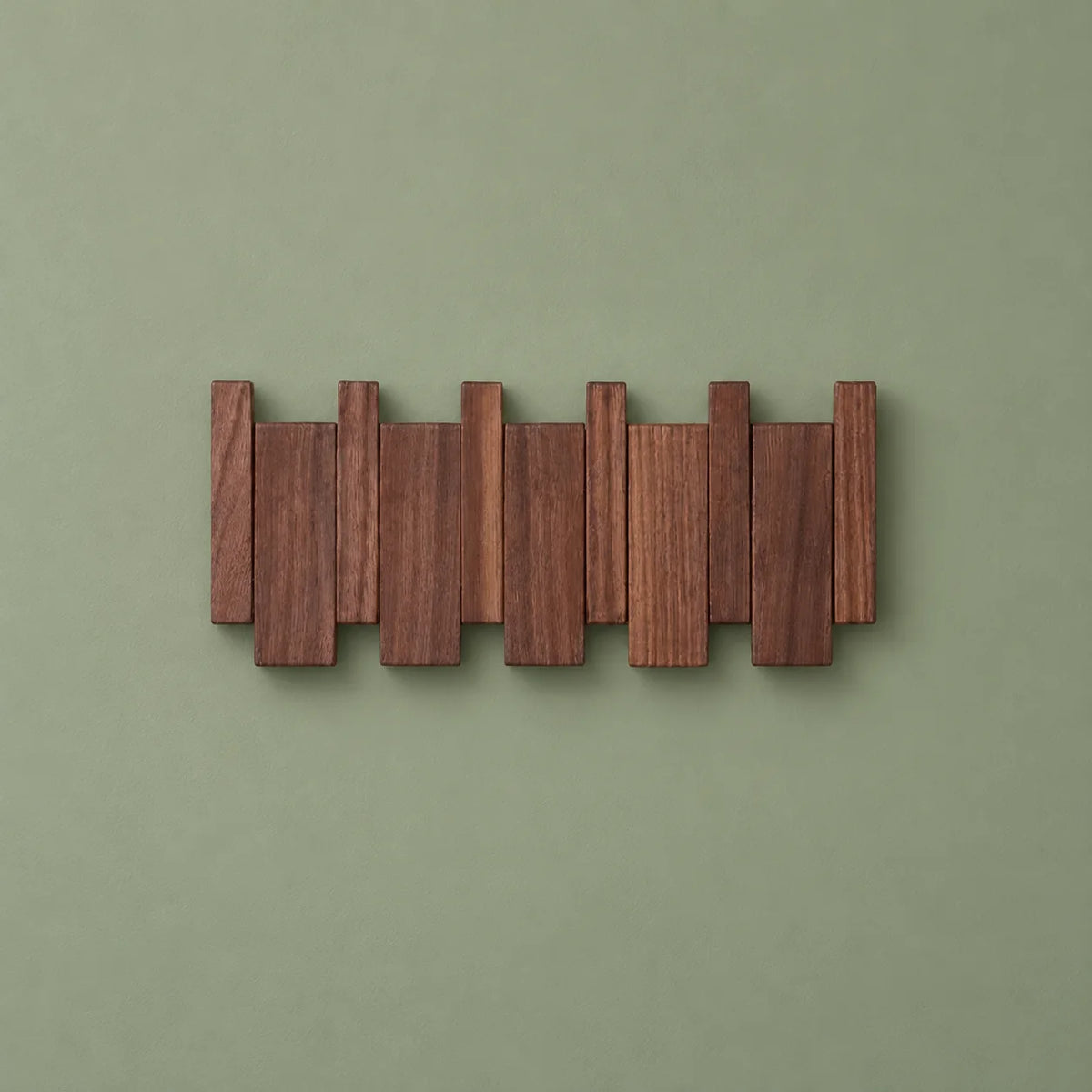 Vue de face du porte-manteau mural compact en bois foncé sur fond vert sauge