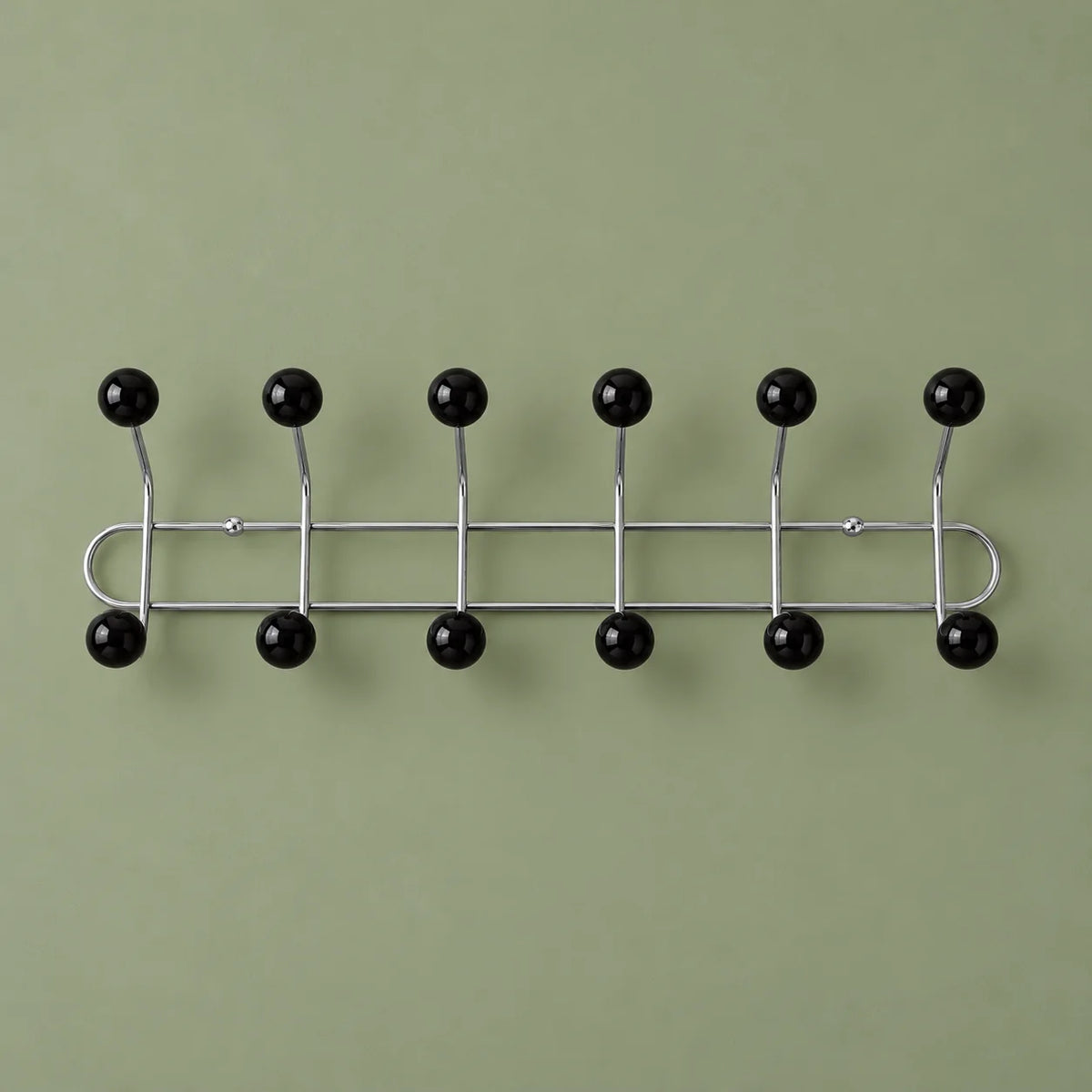 Porte-manteau mural chromé à six bras et douze boules noires sur fond vert sauge