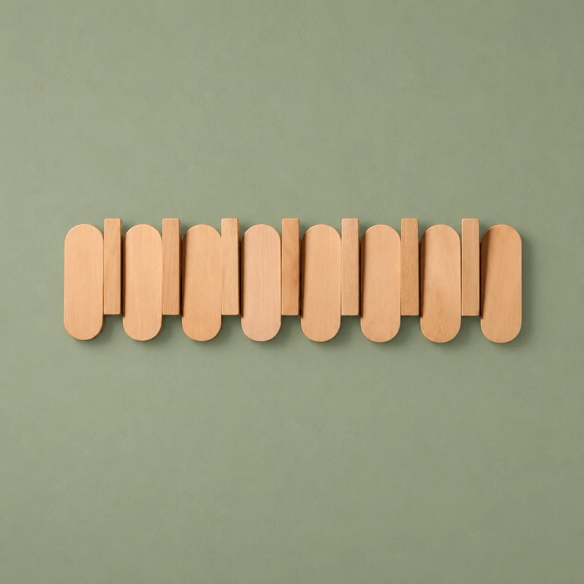 Porte-manteau mural en bois clair vu de face sur fond vert sauge