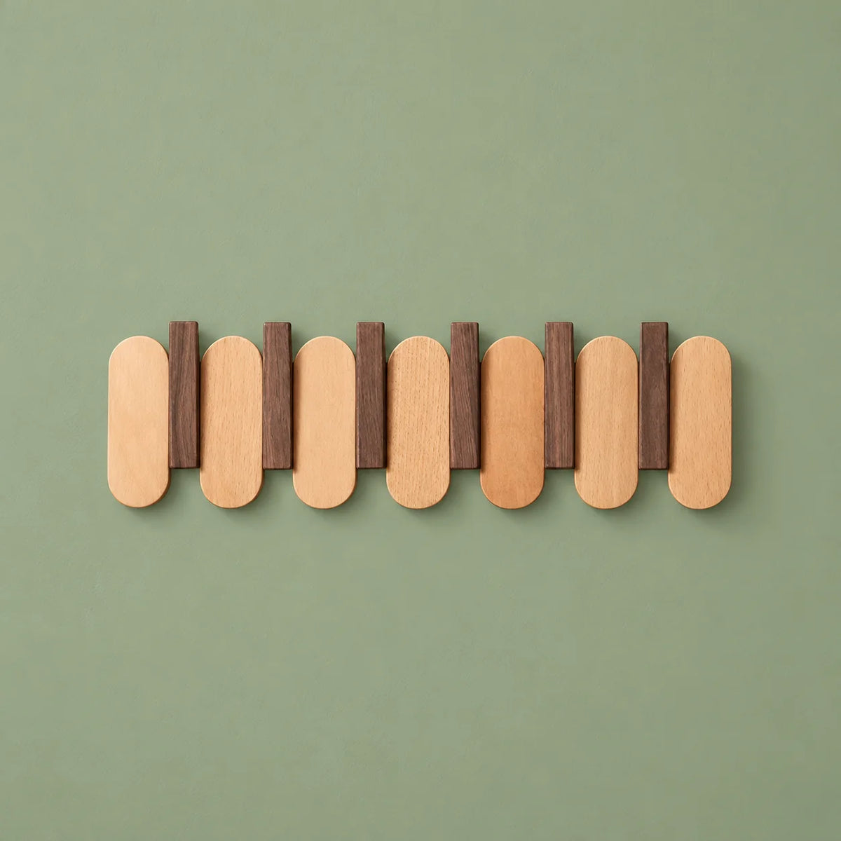 Porte-manteau mural en bois clair et noyer foncé vu de face sur fond vert sauge