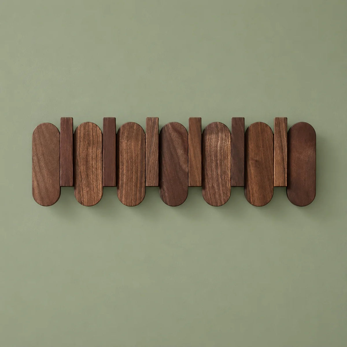 Grand porte-manteau mural en bois foncé vu de face sur fond vert sauge