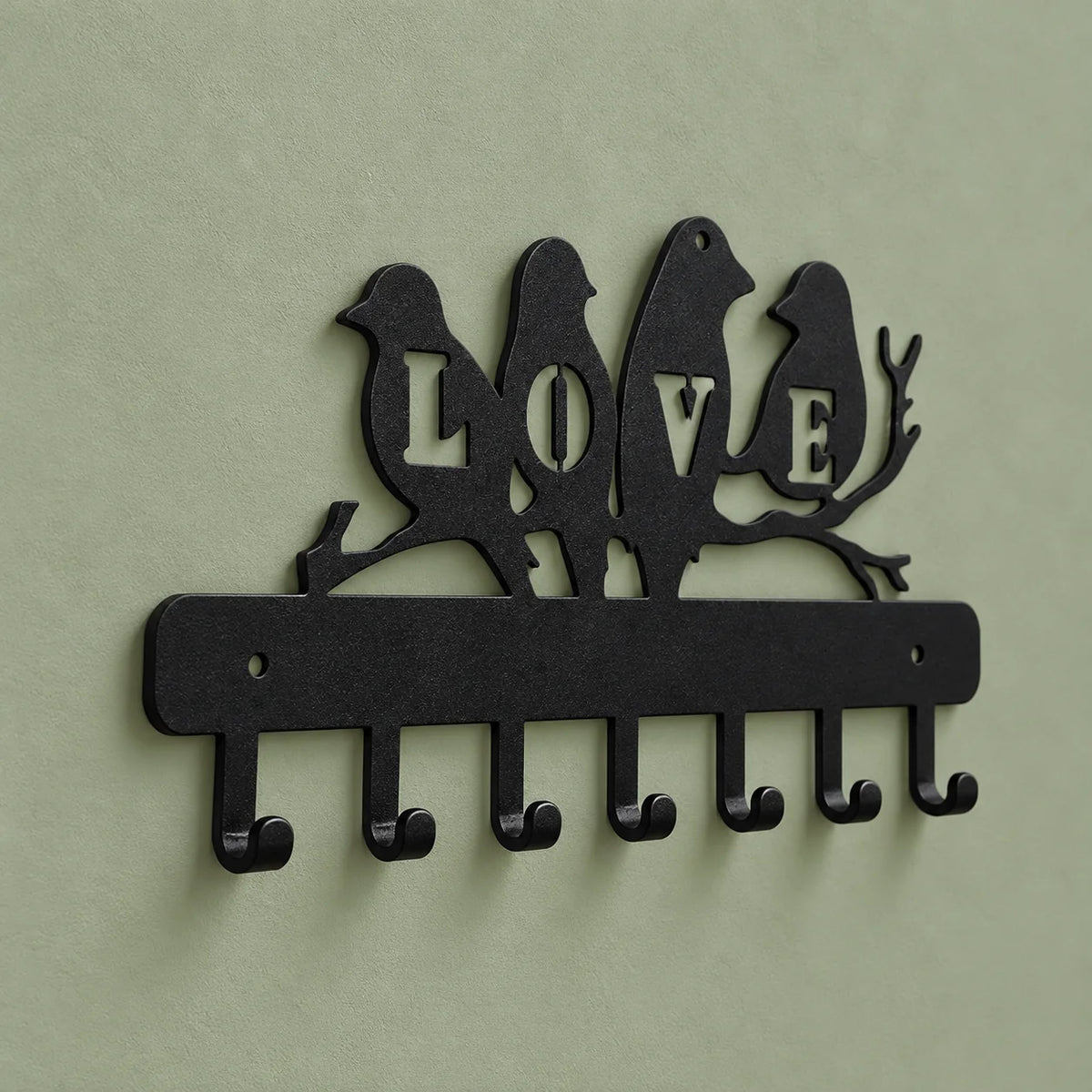 Vue de biais du porte-manteau LOVE noir montrant le relief des crochets sur fond vert
