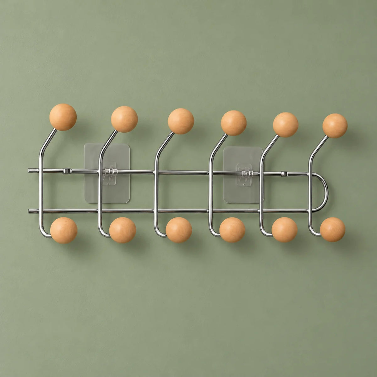 Porte-manteau mural chromé à douze boules abricot sur fond vert sauge