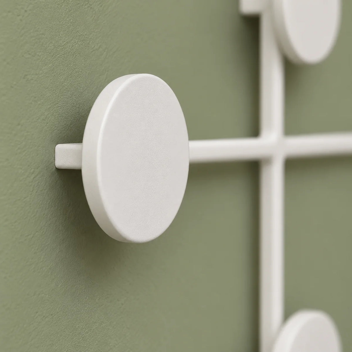 Gros plan sur la pastille et la structure blanche du porte-manteau mural rond