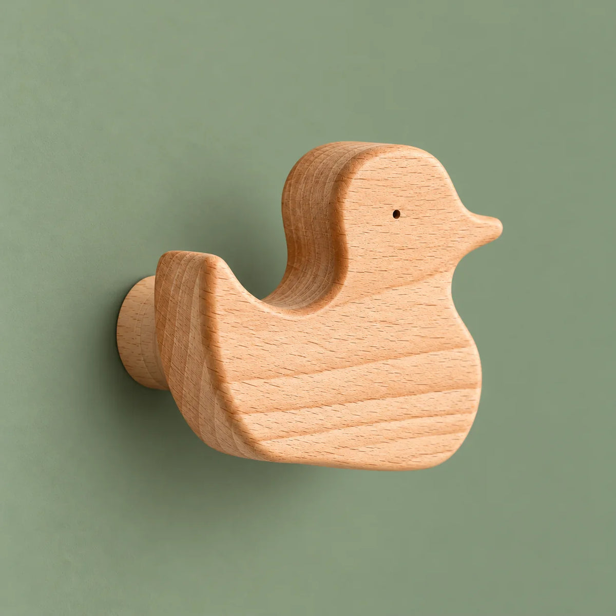 Vue de biais de la patère canard montrant son épaisseur et son support cylindrique sur fond vert