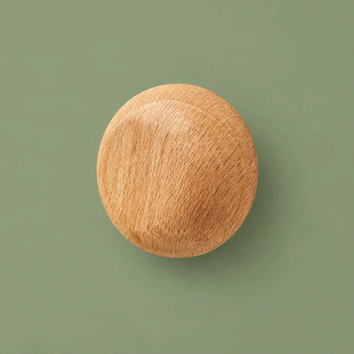 Patère ronde en bois clair vue de face sur fond vert sauge