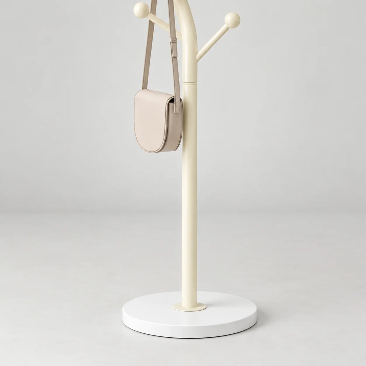 Détail du montant blanc crème, du sac à bandoulière crème et du pied circulaire blanc sur fond gris