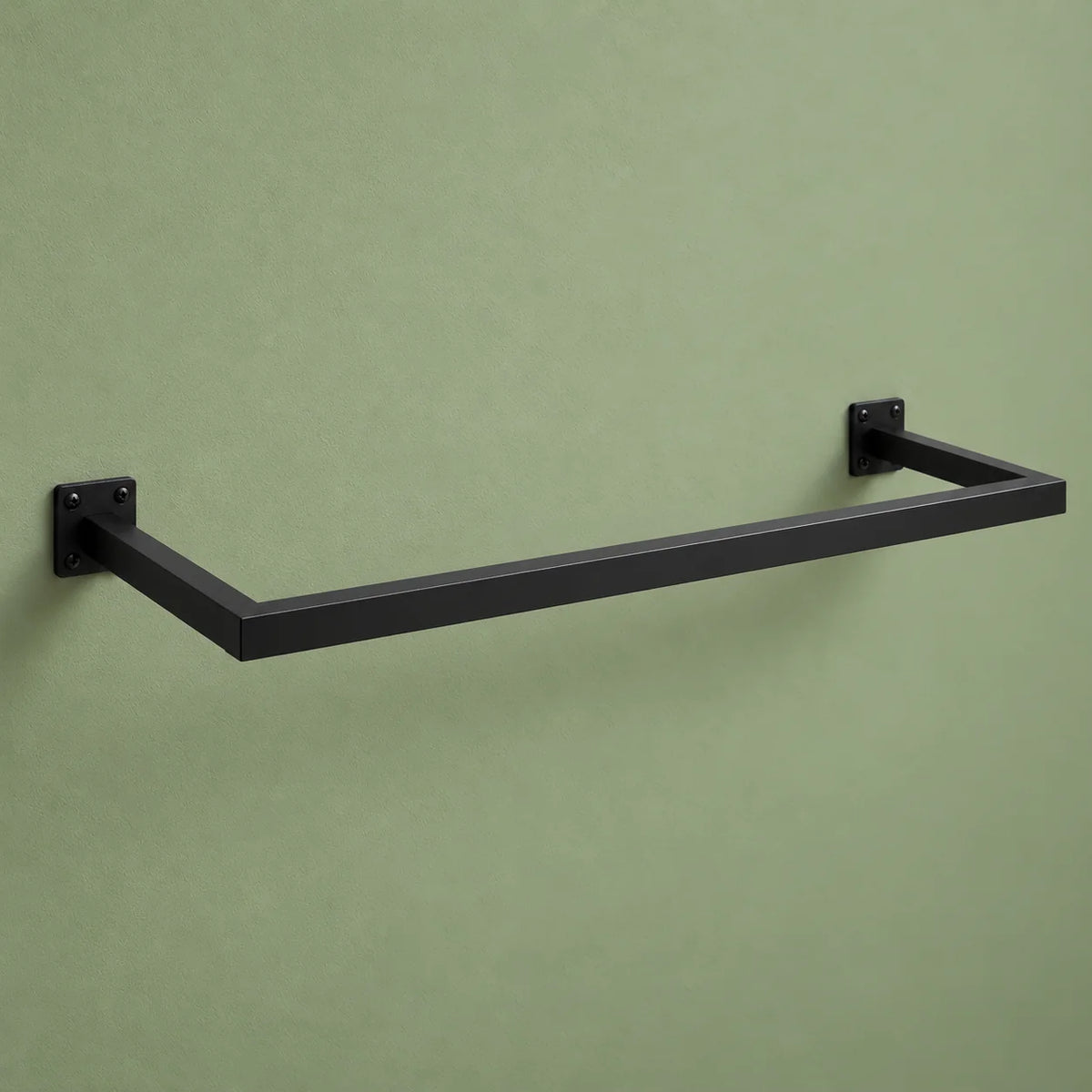 Vue de trois quarts de la barre porte-manteau murale noire sur mur vert sauge