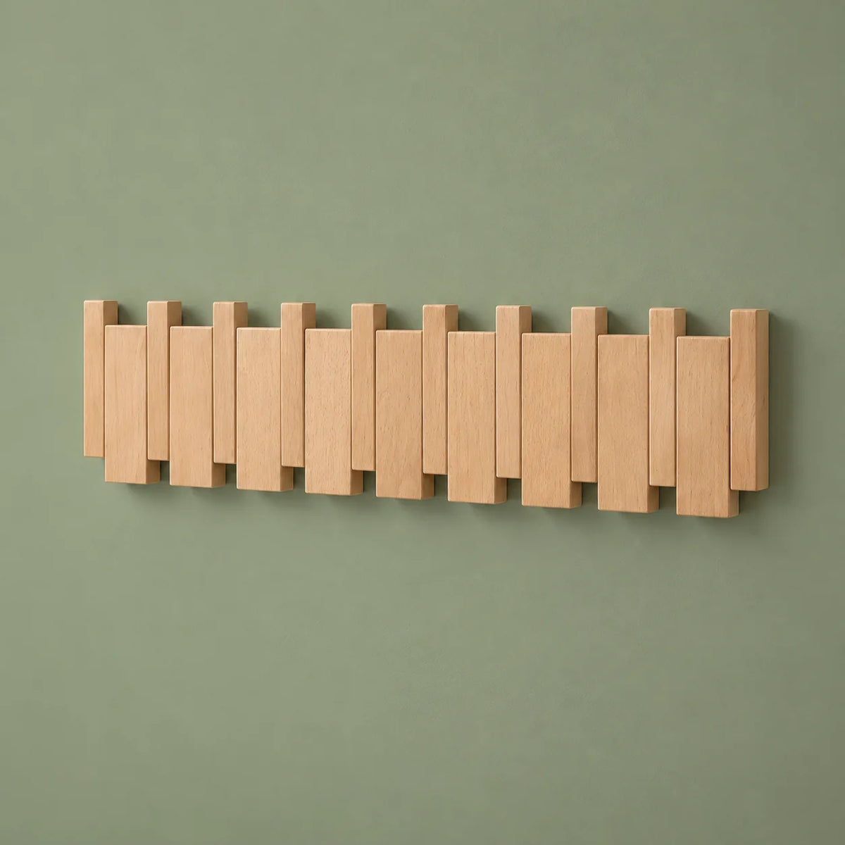 Vue oblique du grand porte-manteau mural en bois clair sur fond vert sauge