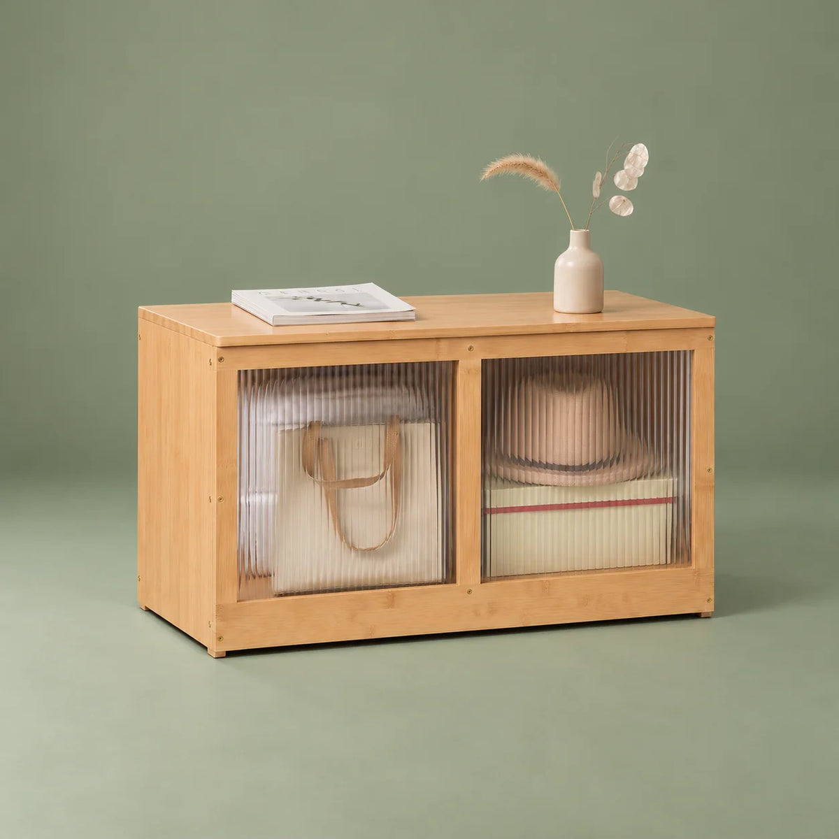 Vue de trois quarts gauche du meuble à chaussures en bambou bois clair sur fond vert sauge