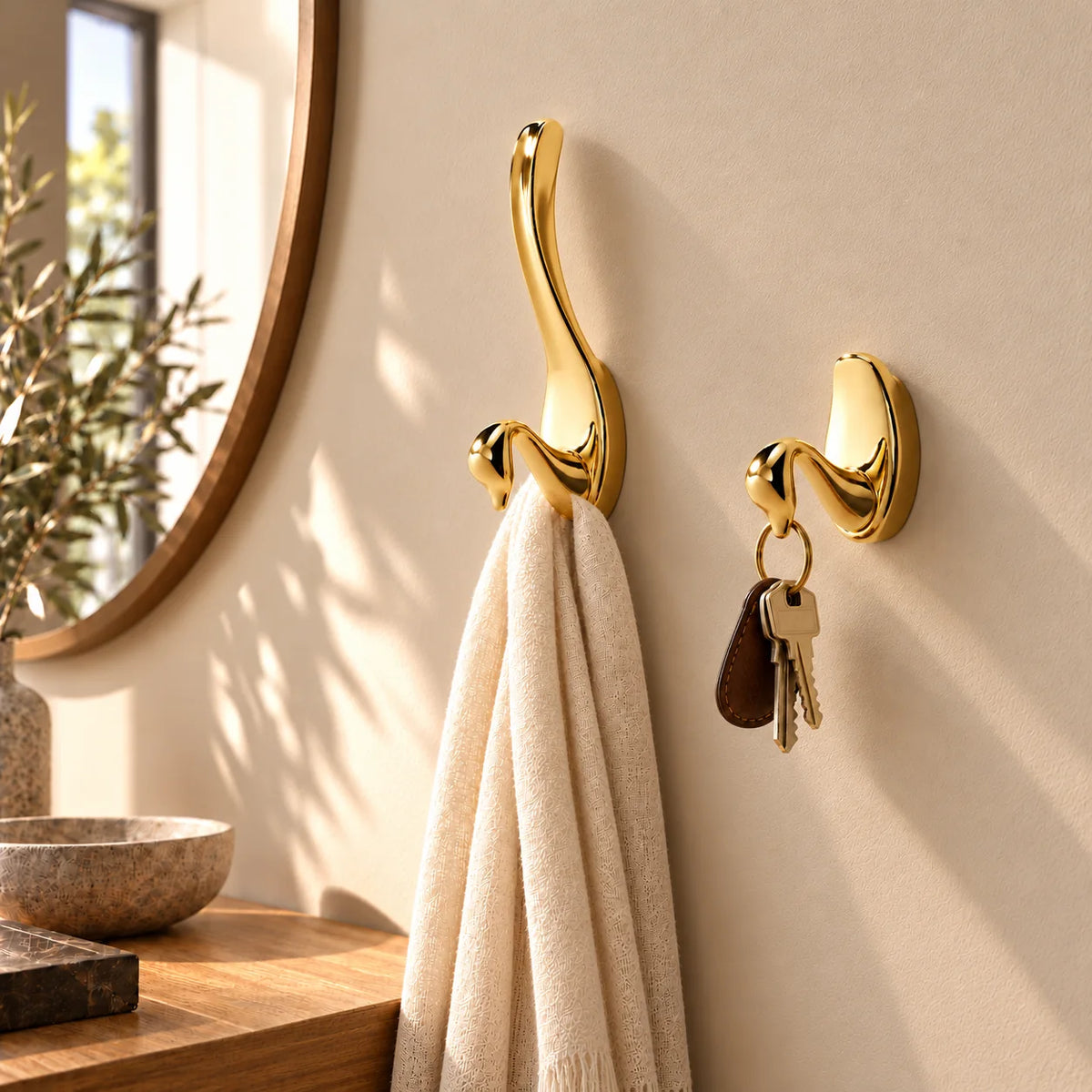 Variantes Grand et Petit des patères cygne à finition dorée brillante installées ensemble dans une entrée
