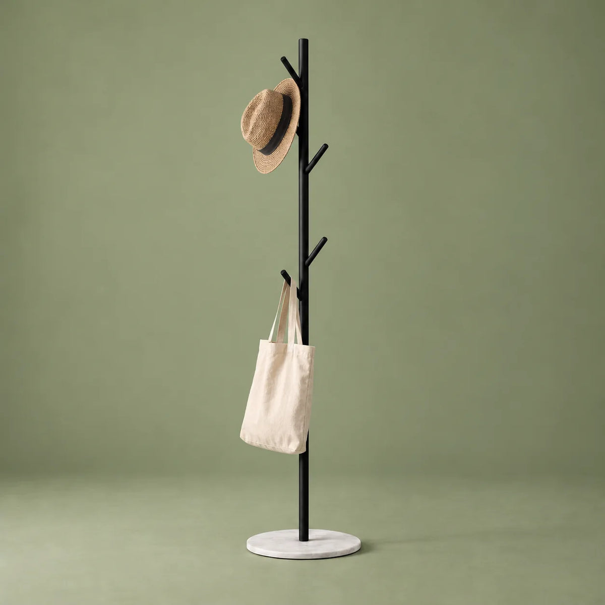 Porte-manteau arbre noir et blanc avec chapeau et sac en toile sur fond vert sauge