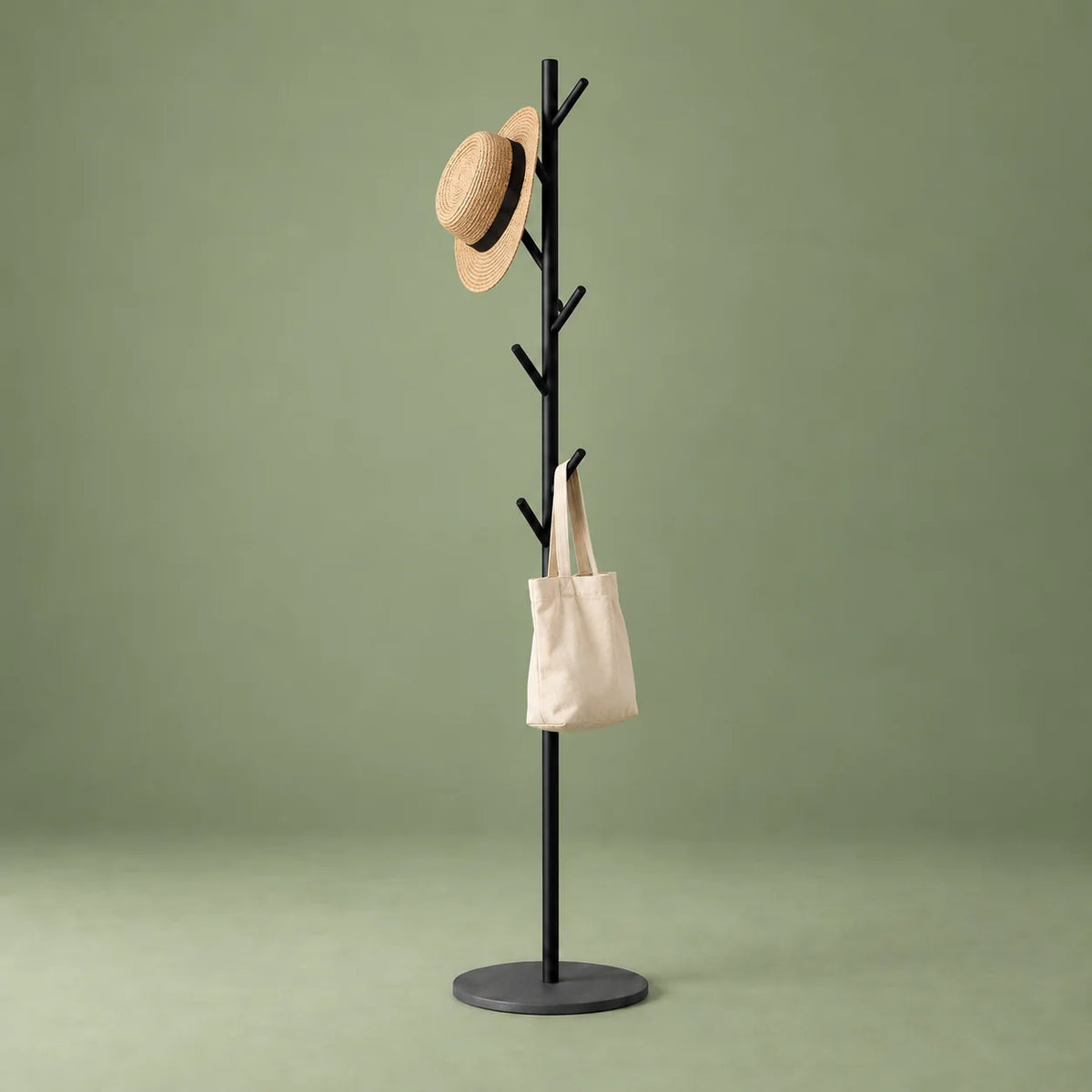 Porte-manteau arbre noir avec chapeau et sac en toile sur fond vert sauge