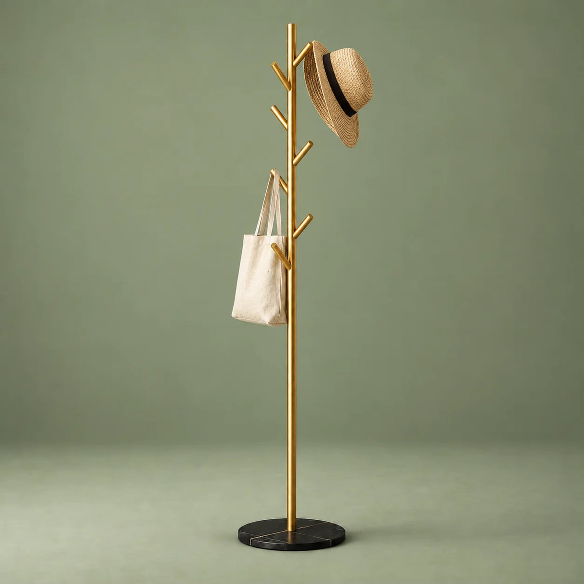 Porte-manteau arbre doré sur base noire avec chapeau et sac en toile sur fond vert sauge