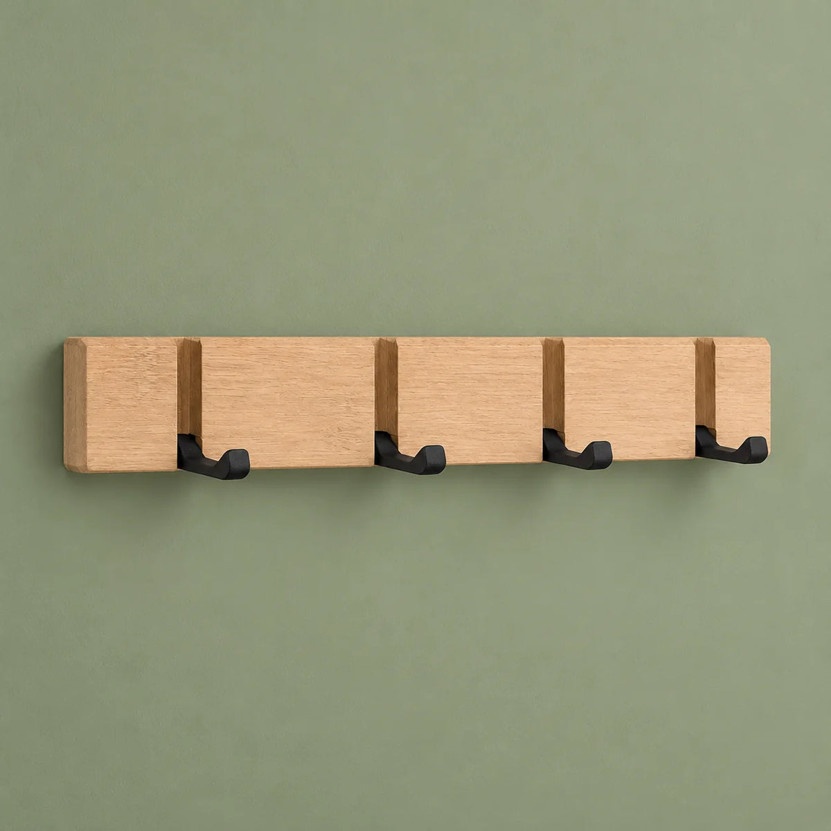 Vue de face du porte-manteau mural en bois beige à quatre crochets sur fond vert sauge