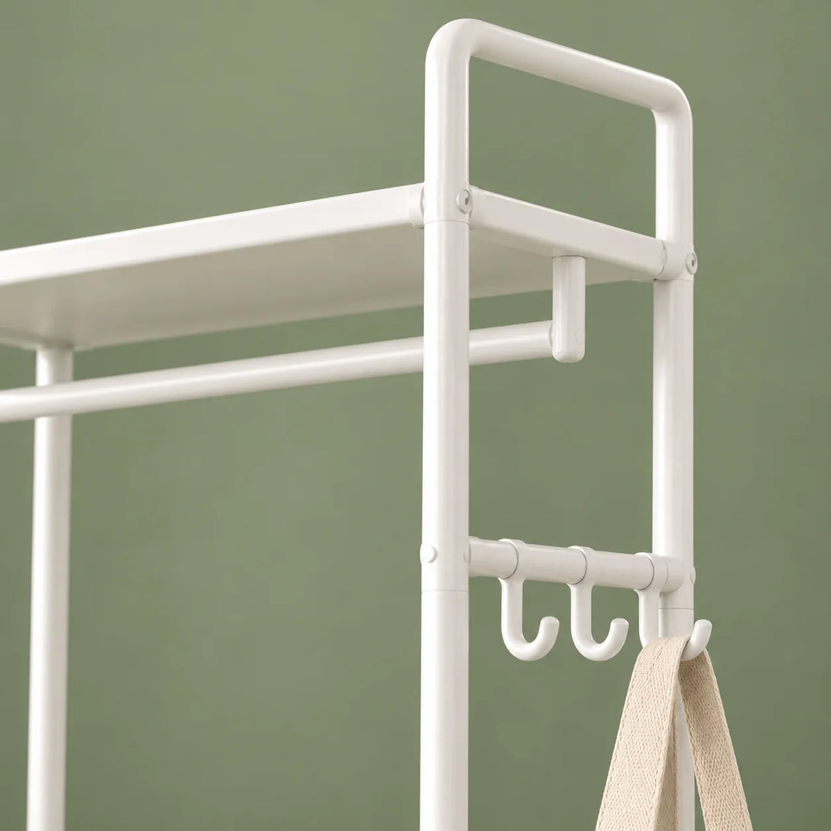 Gros plan des trois crochets latéraux et du métal blanc sur fond vert sauge