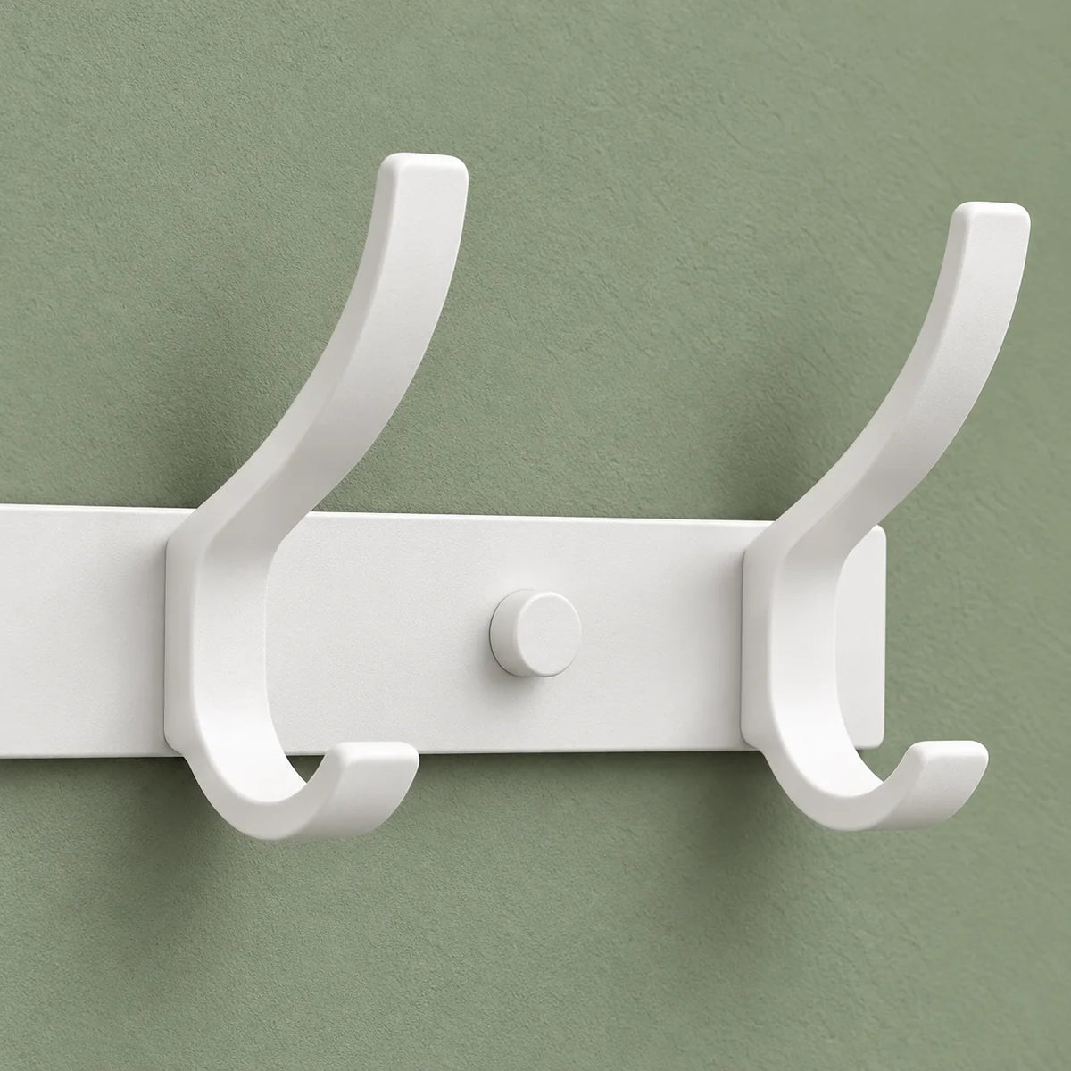Détail des deux crochets blancs de droite et du capuchon de fixation sur fond vert sauge