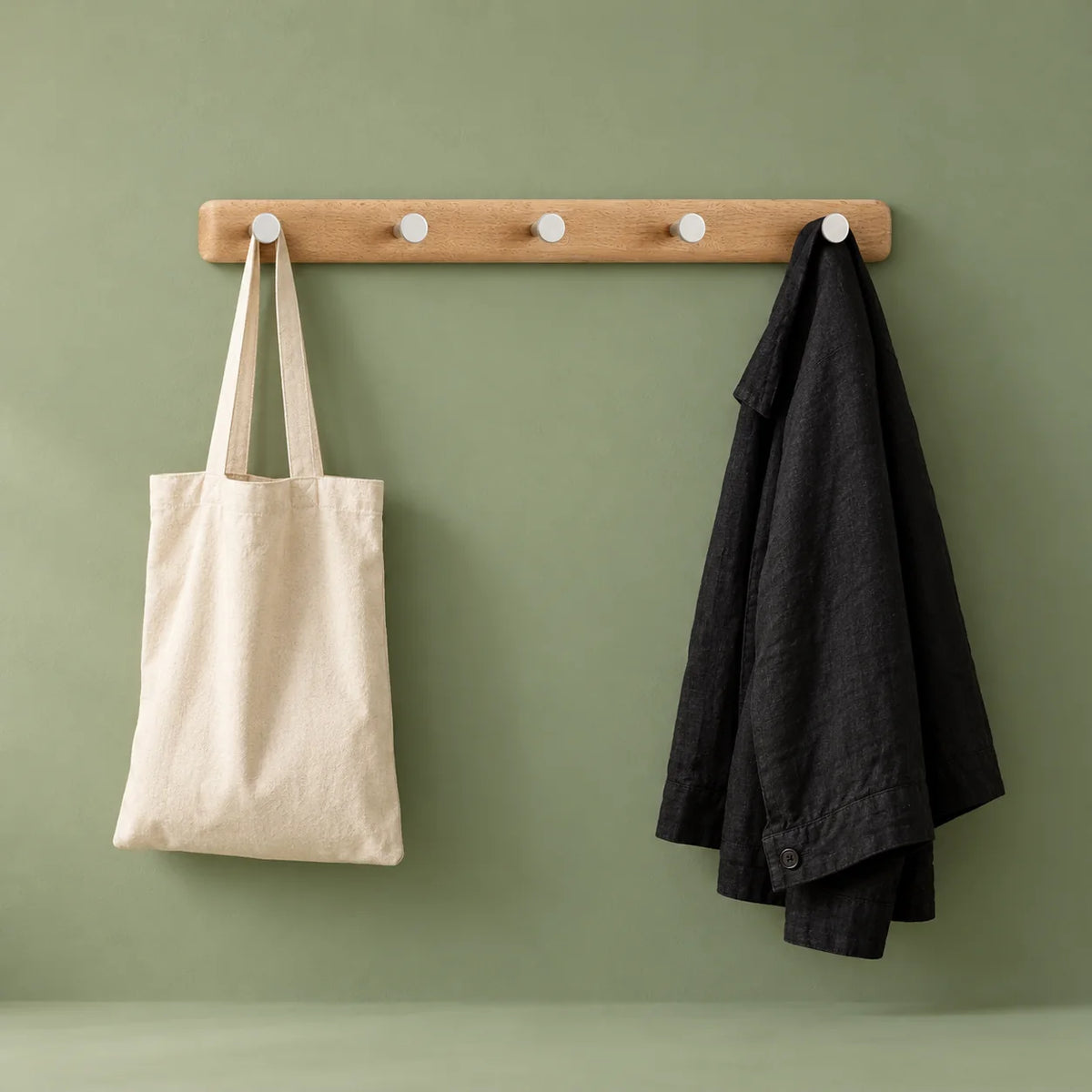 Porte-manteau mural en bois avec sac et veste sur fond vert sauge