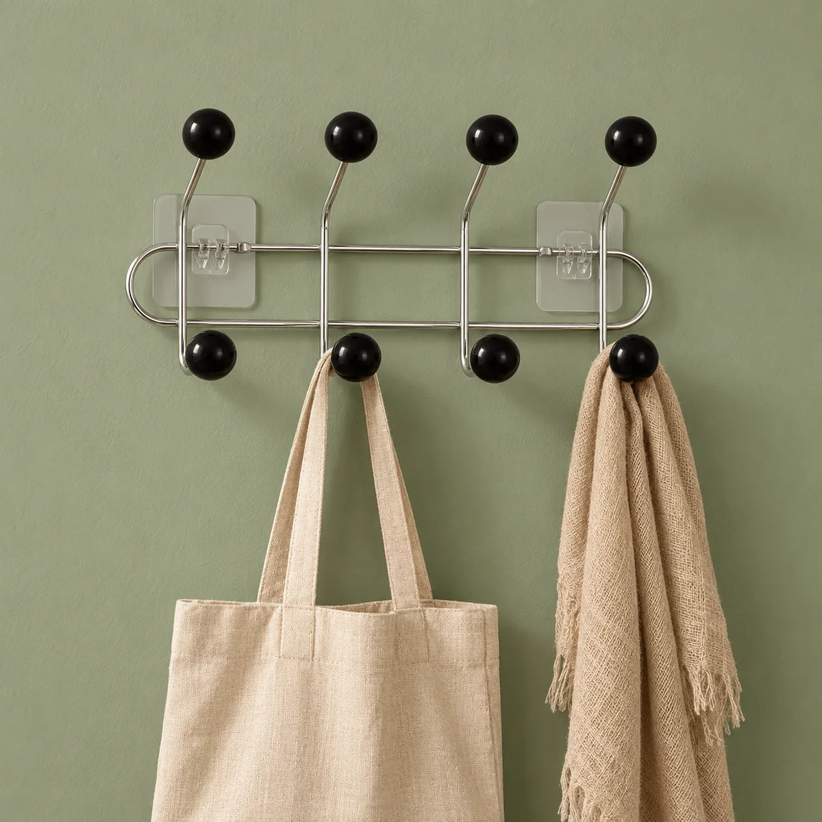 Porte-manteau mural à boules noires avec sac en lin et écharpe sur fond vert