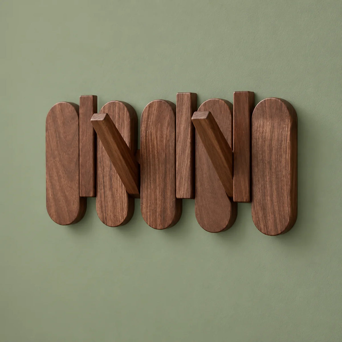 Petit porte-manteau mural en bois foncé avec deux crochets ouverts sur fond vert sauge