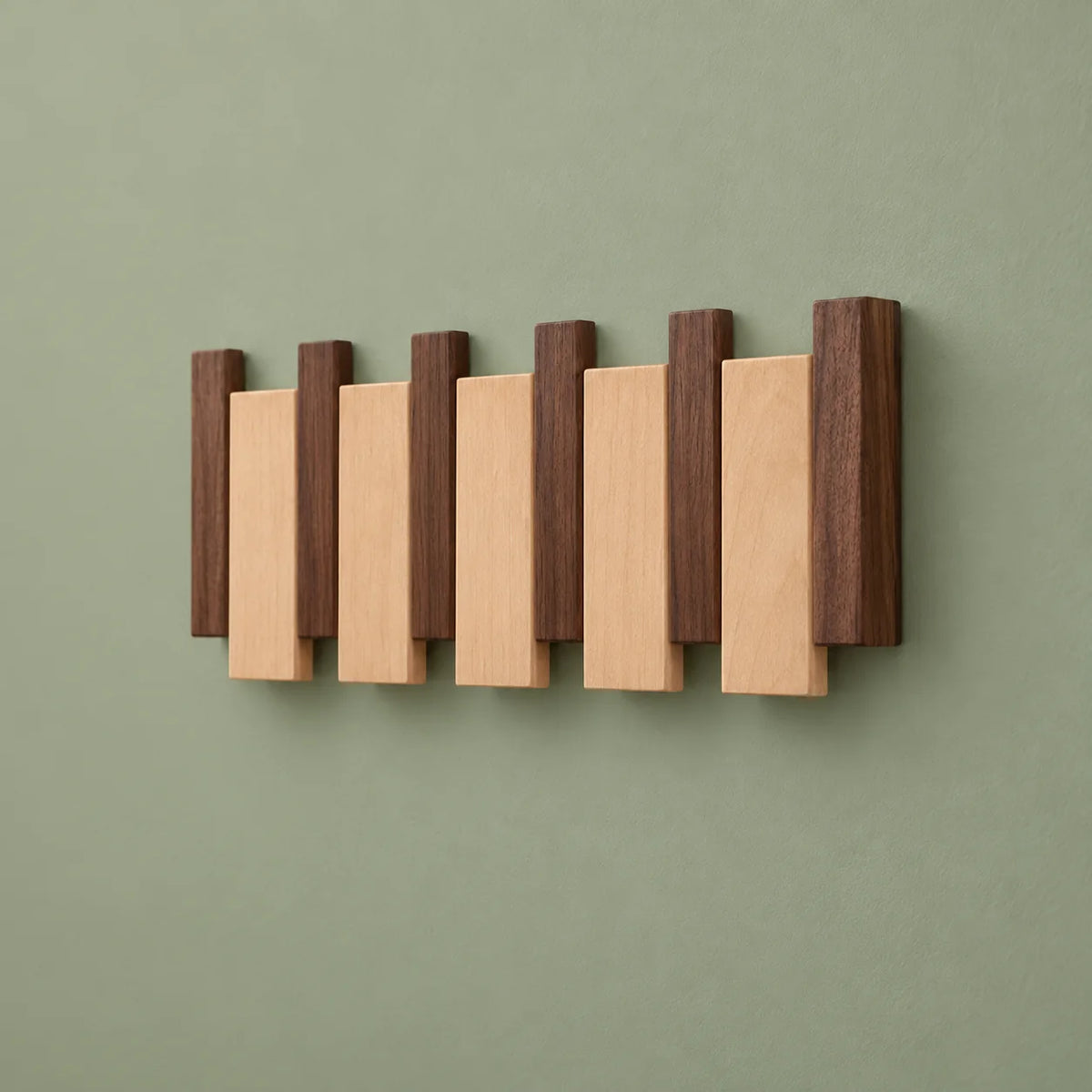 Vue de côté du porte-manteau mural en bois bicolore sur fond vert sauge